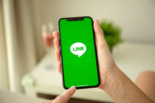 Woman hand holding iPhone X with social networking service Line